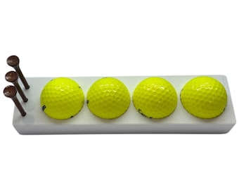 May include: Four bright yellow golf balls are displayed in a white plastic holder. The balls are arranged in a row, with three golf tees in the background.