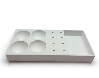 May include: White plastic tray with four round depressions and a section with multiple small holes. The tray is designed for holding and organizing small items.