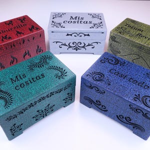 Puede incluir: Cinco pequeñas cajas de madera con diferentes diseños y colores. Las cajas están decoradas con varios patrones y tienen texto en español. El texto en las cajas dice "Mis cositas", "Casi todo", "Baitburrillo", "Mis cositas" y "Totum Revolutrum".