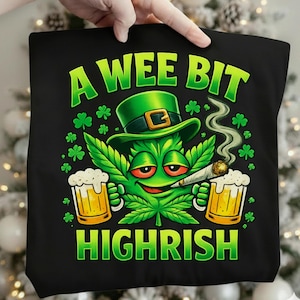 May include: Black tote bag with a green cannabis leaf character wearing a green hat and smoking a joint. The character holds two mugs of beer. Text reads "A Wee Bit Highrish" in green.
