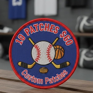 May include: A round blue patch with a red border featuring a baseball, basketball, and hockey sticks. The patch reads "10 Patches $60" and "Custom Patches" in white text. The patch is displayed on a wooden bench.