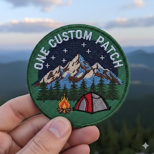 May include: Circular embroidered patch with a camping theme. The patch features a mountain range under a starry night sky, a campfire, and a tent. The text "ONE CUSTOM PATCH" is embroidered around the edge in white.