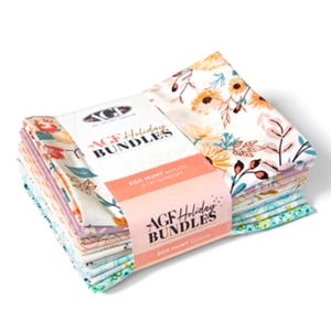 May include: A stack of 11 fabric squares with floral patterns in shades of pink, white, and green. The fabric squares are bundled together with a pink and white label that reads "AGF Holiday Bundles Egg Hunt Edition 11 Fat Quarters".