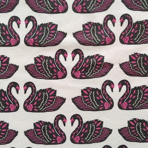 May include: White fabric with a repeating pattern of black swans with pink accents. The swans are facing each other with their necks intertwined.