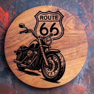 May include: A wooden coaster with a Route 66 motorcycle design. The black motorcycle graphic is set against a light brown wooden background. The Route 66 sign is above the motorcycle. The coaster is round.