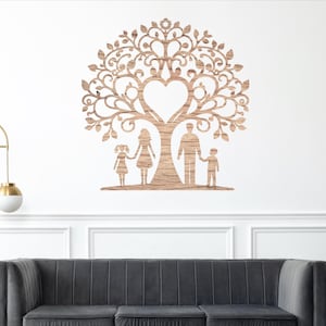 May include: A wooden family tree wall art piece. The tree features a heart-shaped center and a family of four standing beneath it. The art is mounted on a white wall above a gray sofa, with a gold lamp and a potted plant nearby.