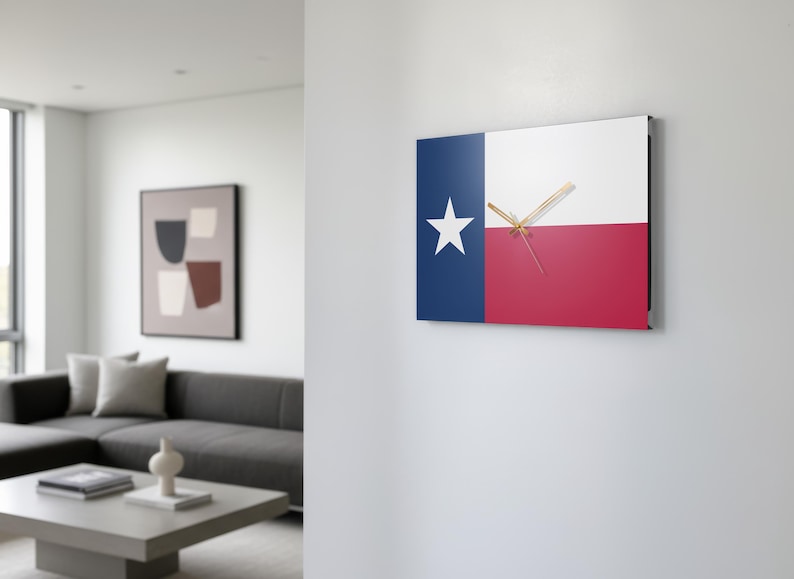 K&ouml;nnte beinhalten: Quadratische Wanduhr mit dem Design der Texas-Staatsflagge. Das Zifferblatt ist in blaue, wei&szlig;e und rote Abschnitte unterteilt, mit einem wei&szlig;en Stern auf der blauen Seite. Goldfarbene Zeiger zeigen die Uhrzeit an. Die Uhr ist an einer wei&szlig;en Wand befestigt.