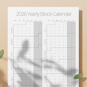 Puede incluir: Calendario de bloques anual de 2026 en blanco con un diseño minimalista. El calendario presenta un diseño de cuadrícula con meses y días etiquetados. Las palabras "BUY NOW" están en la parte inferior. Hojas verdes esparcidas.