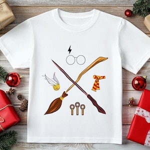 May include: White t-shirt featuring a crossed broom and wand design with glasses, a lightning bolt, a golden snitch, and a scarf. The shirt is surrounded by Christmas decorations, including red ornaments and wrapped gifts.