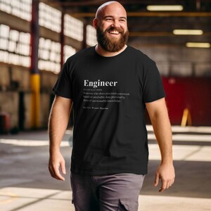 May include: A black short-sleeved t-shirt featuring white text that defines the word Engineer as someone who does precision guesswork based on unreliable data provided by those of questionable knowledge, with a See Also line for Wizard and Magician.