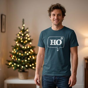 May include: A dark teal short-sleeved t-shirt featuring a white graphic of a speech bubble containing the text HO cubed. The design is centred on the chest of the shirt. The garment has a crew neckline and a standard fit, constructed from fabric.