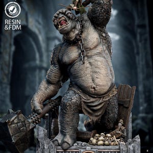 Könnte beinhalten: Harzstatue eines Trolls aus "Der Herr der Ringe". Der graue Troll mit Kette hält einen Streitkolben. Eine Elfenfigur steht auf seiner Schulter. Der Sockel zeigt das Filmlogo und Schädel. Maßstab 1:8.
