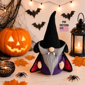 May include: A Halloween-themed scene featuring a carved pumpkin, a crochet gnome in a black hat and purple cloak, and decorative spiders. The gnome has a gray beard and a beige nose. A lit candle and fall leaves complete the festive display.