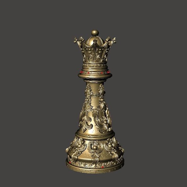 May include: A gold-colored chess queen piece with intricate, ornate detailing. The piece features a crown design at the top and is adorned with red accents. The base and stem are elaborately carved with floral and scroll patterns.