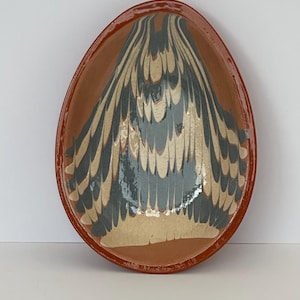 May include: A terracotta oval serving dish with a marbled design in shades of grey and beige.