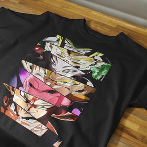 May include: Black t-shirt featuring a graphic design of various anime character faces in a fragmented, layered style. The design incorporates a range of colors, including orange, pink, yellow, and green. The shirt is made of a soft material.
