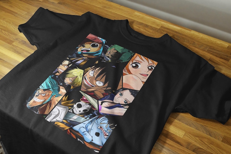 May include: Black t-shirt featuring a colorful collage of anime characters. The graphic includes various faces and figures from the anime series. The shirt is made of a dark fabric and is displayed on a wooden surface.