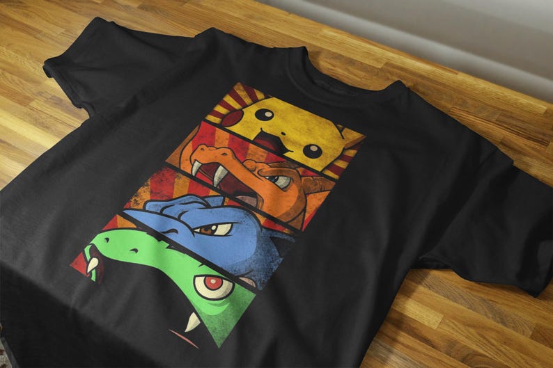 May include: Black t-shirt featuring a graphic design of three cartoon characters in separate panels. The top panel shows a yellow character, the middle panel shows an orange character, and the bottom panel shows a blue and green character.