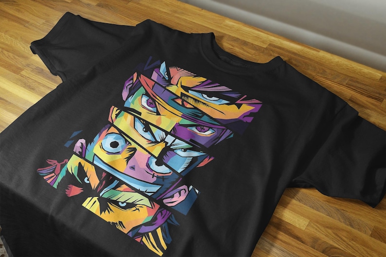 May include: Black t-shirt featuring a vibrant, pop art style design of multiple anime-style faces with colorful eyes and facial features. The design is composed of geometric shapes and bold colors, creating a striking visual effect.