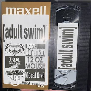 May include: A gold VHS tape with the text "maxell" and "[adult swim]" printed on the front. The tape features a collection of Adult Swim shows including "Metalocalypse", "Harvey Birdman, Attorney at Law", "Tom Goes to the Mayor", "12 oz Mouse", "Aqua Teen Hunger Force", and "Moral Orel". The tape also includes the text "+MOREJ 4 HOURS - EPMODE" and "VHS".