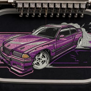 Puede incluir: Un diseño de bordado sobre tela negra que muestra un coche deportivo morado con ruedas blancas, capturado dentro de un bastidor de bordado ovalado. El coche aparece en movimiento de derrape con estelas de humo blanco sobre un marco rosa.
