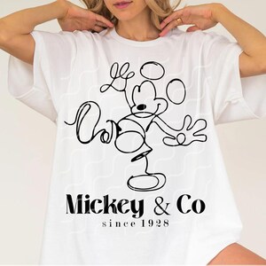 May include: White t-shirt with a black line drawing of Mickey Mouse and the text "Mickey & Co. since 1928"