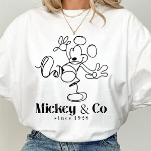 May include: White t-shirt with a black line drawing of Mickey Mouse and the text "Mickey & Co since 1928"