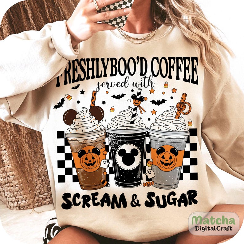 May include: Cream-coloured sweatshirt with a Halloween graphic. The design shows three coffee cups with whipped cream, pumpkins, and the text "FRESHLYBOO'D COFFEE served with SCREAM & SUGAR". Bats and candy corn are also included.
