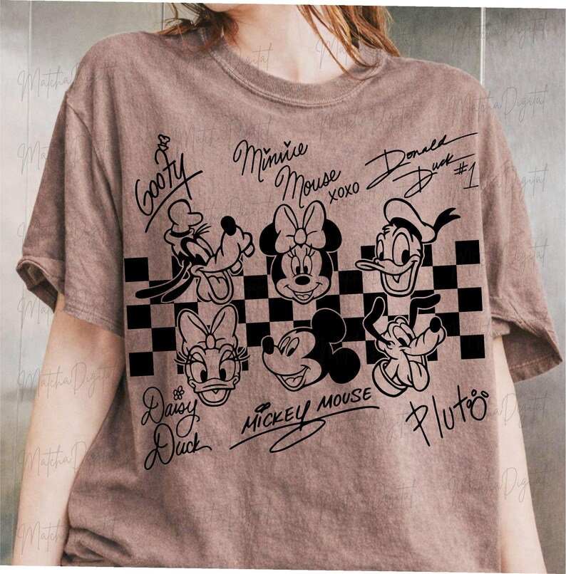 May include: A brown t-shirt featuring black line art of Disney characters including Goofy, Minnie Mouse, Donald Duck, Daisy Duck, Mickey Mouse, and Pluto. The characters are arranged above a black and white checkered pattern.