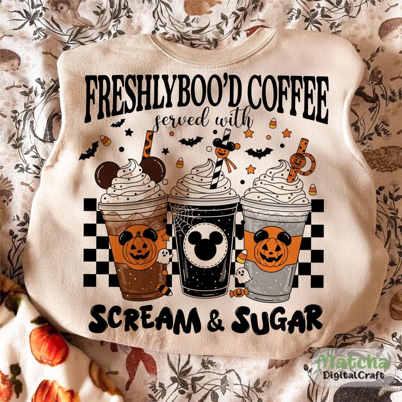 May include: Cream sweatshirt with a Halloween design. It shows three coffee cups with whipped cream, pumpkins, and Mickey Mouse silhouettes. The text reads "FRESHLYBOO'D COFFEE served with SCREAM & SUGAR."