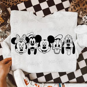 May include: A light gray sweatshirt featuring a black and white graphic of Disney characters: Minnie Mouse, Goofy, Mickey Mouse, Donald Duck, and Pluto. The sweatshirt is displayed on a black and white checkered surface.