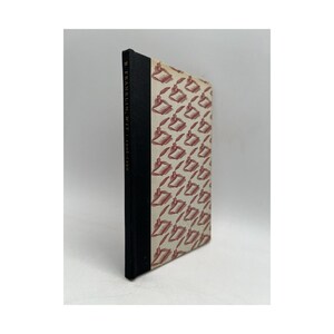 May include: A vintage book with a black spine and a patterned cover featuring red inkwells and quills on a cream background. The book's spine reads "B. Franklin, Jr. 1706-1790".