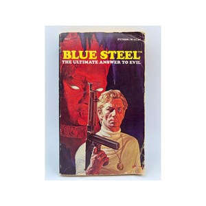 May include: Vintage paperback book cover for "Blue Steel: The Ultimate Answer to Evil." The cover features a man holding a machine gun, with a red-toned face in the background. The title is in yellow, with the author's name at the top.
