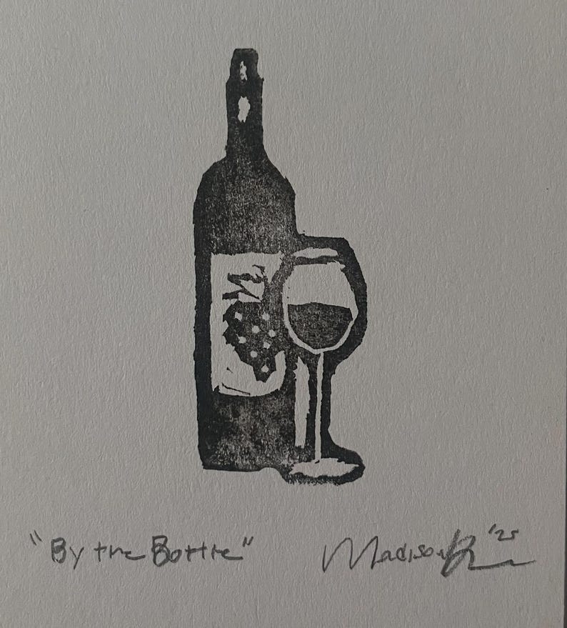 May include: A black ink block print on white paper featuring a wine bottle with a grape cluster graphic and a stemmed wine glass. The text "By the Bottle" is printed in the lower left corner, with a handwritten signature and the year '25 on the right.