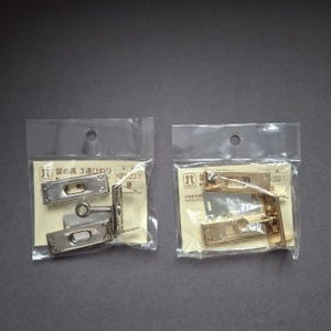 May include: Two small plastic bags containing metal hardware. One bag holds silver-colored hardware, and the other holds gold-colored hardware. Each bag has a small hole at the top and a paper insert with Japanese text.
