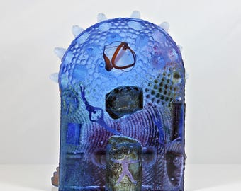 May include: A blue glass sculpture with a textured surface and a variety of colours and shapes. The sculpture is reminiscent of an underwater scene with a starfish, fish, and other marine life.