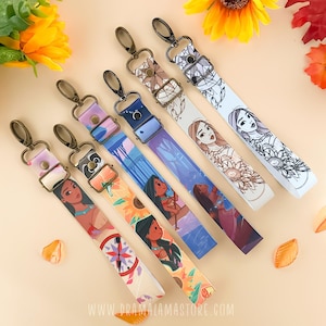 Puede incluir: Seis correas de bolso coloridas con varios diseños. Cada correa presenta un patrón diferente, incluyendo floral, ilustraciones de personajes y formas geométricas. Las correas tienen cierres metálicos dorados y hebillas ajustables.