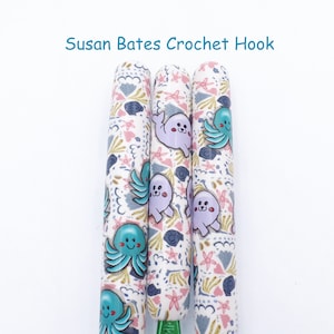 May include: Three Susan Bates crochet hooks with a white background and a colorful pattern of sea creatures, including seals and octopuses.