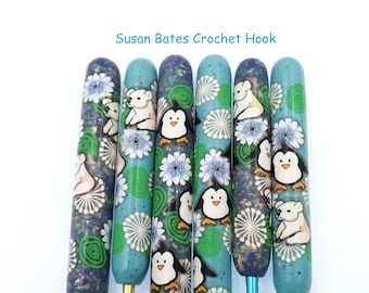 May include: A set of six Susan Bates crochet hooks with colorful, whimsical designs. The hooks feature penguins, polar bears, and floral patterns on a teal background.