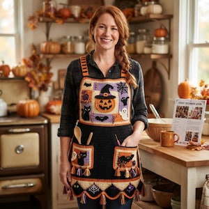 May include: A black crochet apron featuring a Halloween-themed patchwork design with orange, purple, and white accents. The apron displays motifs of a jack-o'-lantern, black cats, ghosts, bats, and spiderwebs, finished with decorative fringe along the hem.