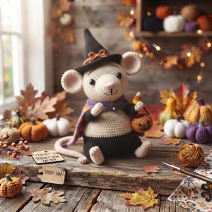 Könnte beinhalten: Ein gehäkeltes Maus-Spielzeug mit einem schwarzen Hexenhut mit orangefarbener Schleife und einem violett-orangen Umhang. Die Maus hat cremefarbenes Fell, eine schwarze Hose und hält einen kleinen orangefarbenen Kürbiseimer. Zwei Holzschilder zeigen Spooky Sam.