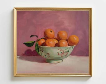 May include: A still life painting of a bowl filled with oranges. The bowl is light green with a floral pattern. The oranges are bright orange and have green leaves attached. The background is a solid pink color, and the painting is in a gold frame.