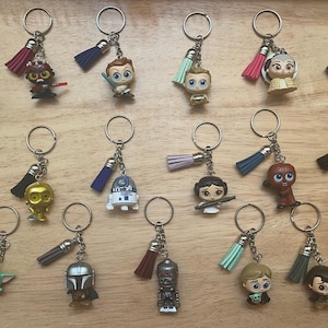 May include: A selection of character keyrings featuring figures from a popular science fiction franchise. Each keyring has a metal ring, a small character figurine, and a tassel in various colours.