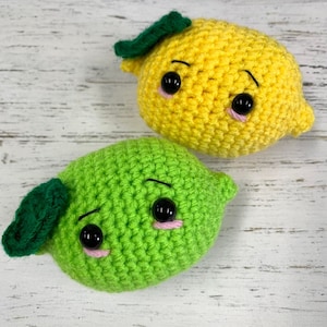May include: Two crocheted fruit toys, a yellow lemon and a green lime, with embroidered eyes and pink cheeks.