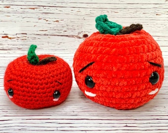 May include: Two crocheted red apples with embroidered eyes and smiles. The larger apple is slightly larger than the smaller apple.