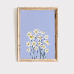May include: A framed floral print featuring a cluster of white daisies with yellow centers and green stems against a light blue background. The frame is a distressed gold color, adding a vintage touch to the artwork.