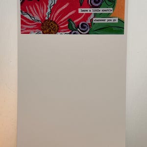 May include: A white notepad with a colorful floral design and the text "leave a little sparkle wherever you go" at the top.