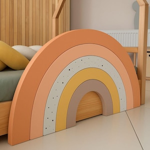 May include: A multi-coloured wooden rainbow headboard in shades of orange, peach, yellow, and grey with black dots. The headboard is part of a wooden bed frame, creating a whimsical design for a child's bedroom.