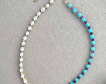 Peut inclure: Un collier en chaîne dorée avec des perles blanches et des perles turquoise et violettes. Le collier est composé de perles blanches pour moitié et de perles turquoise et violettes pour l'autre moitié.