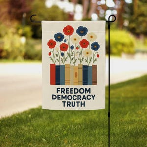 May include: A garden flag featuring a floral design with red, blue, and white flowers. The flowers are arranged above a row of books in various colors. The words "FREEDOM DEMOCRACY TRUTH" are printed in navy blue.